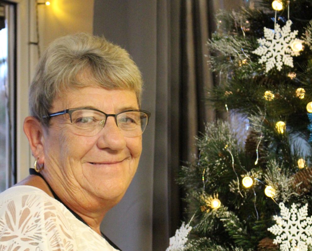 Head and shoulders of Maggie Waring next to Christmas Tree